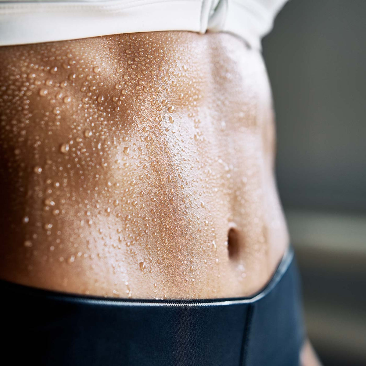 Digestion and Gut Health Woman's abdomen close up with water droplets on skin.