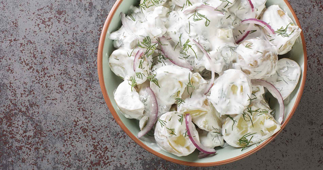 Creamy Nordic Potato Salad, with red onion and freshly chopped dill close-up in a plate
