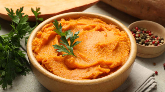 Bowl of Mashed Sweet Potatoes with parsley on a light background