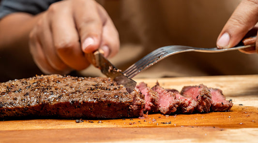 Person cutting meat with a knife and fork