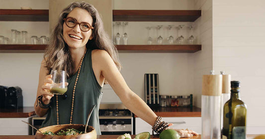 woman smiling while holding some green juice