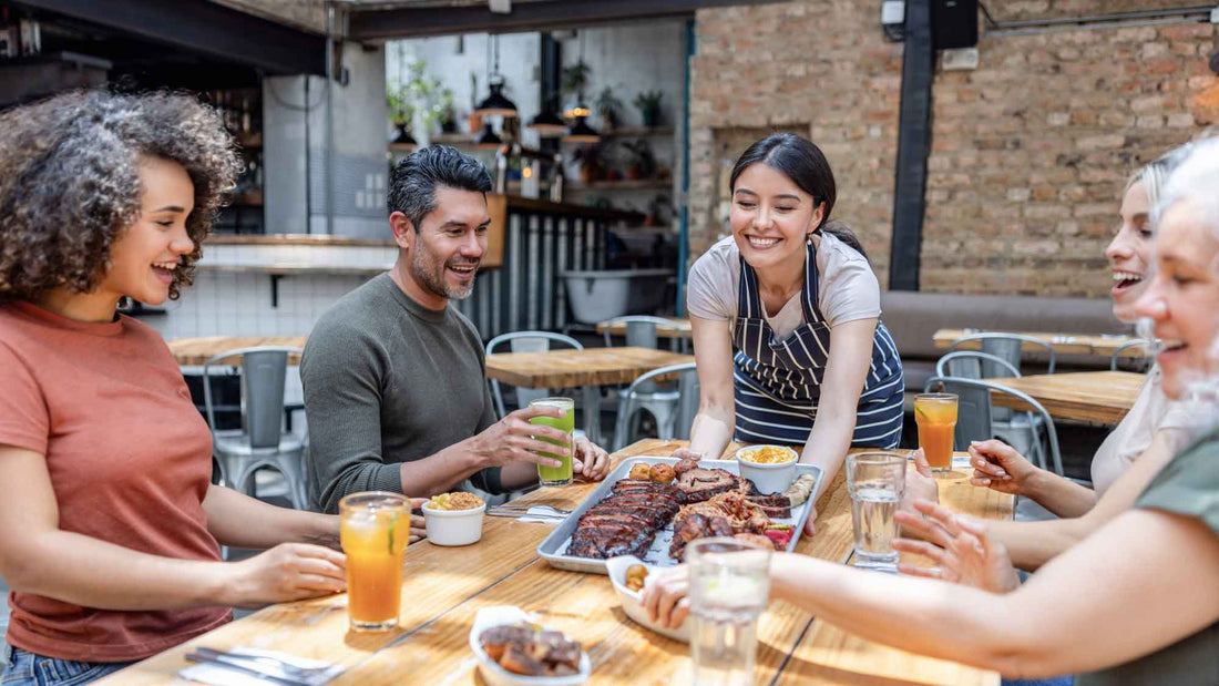 waitress serving a tray of meat to a group of people at a restaurant