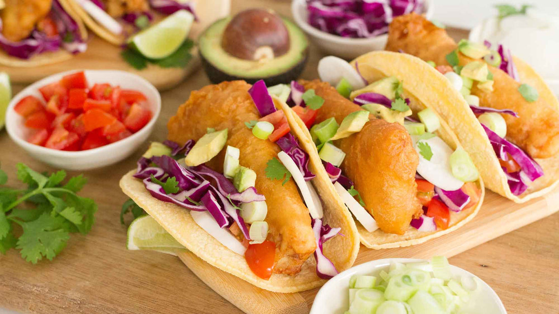Fried Cod Fish Tacos, served with fresh shredded red cabbage, radishes, tomatoes, scallions, avocado, cilantro, and lime on a corn tortilla