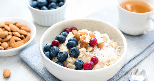 Bowl of overnight oatmeal with berries and coconut flakes with cup of tea.