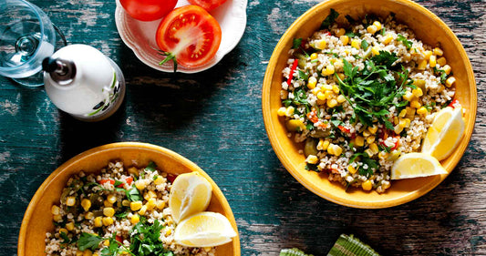 Bowls of quinoa with corn, lemon slices, and greens