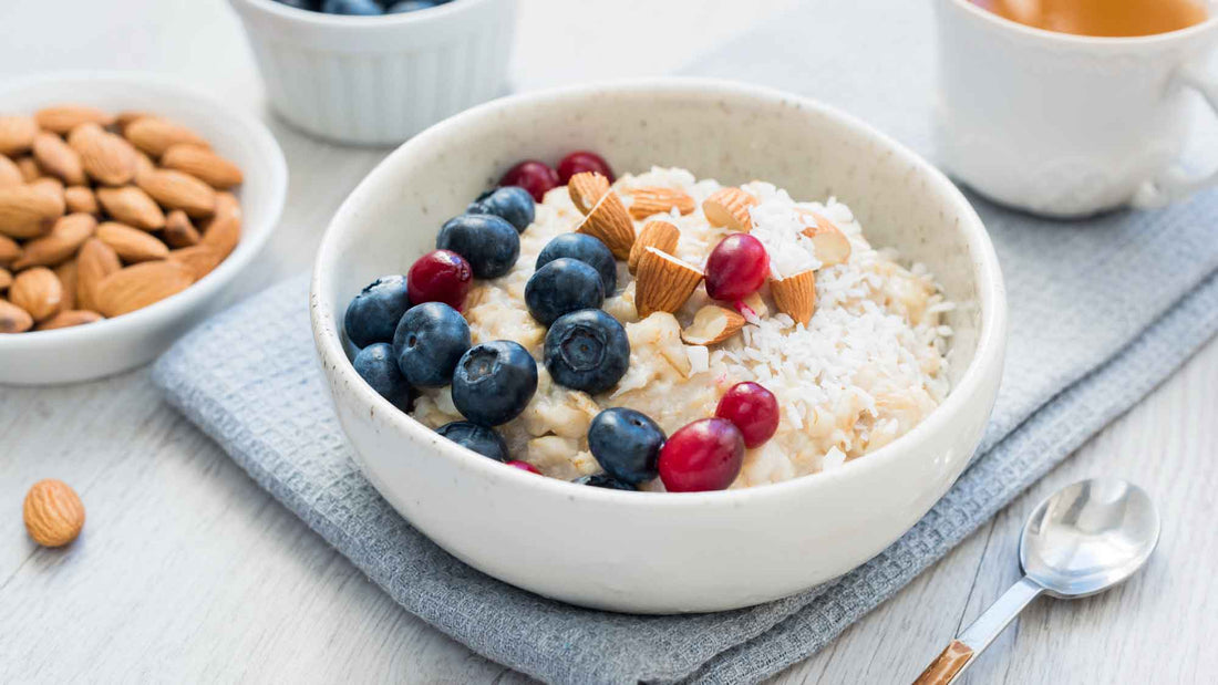 Bowl of overnight oatmeal with berries and coconut flakes with cup of tea.