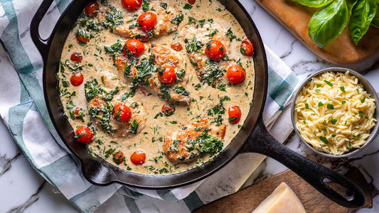 Creamy Parmesan chicken thighs in a skillet with spinach, cherry tomatoes, and orzo
