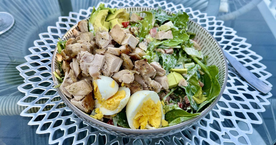 Salad with chicken, boiled egg, avocados, and greens
