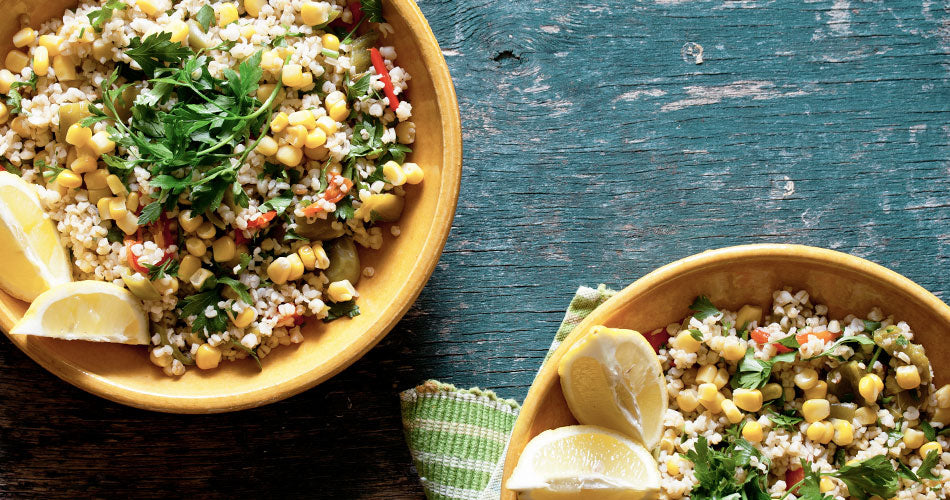 Bowls of quinoa with corn, lemon slices, and greens