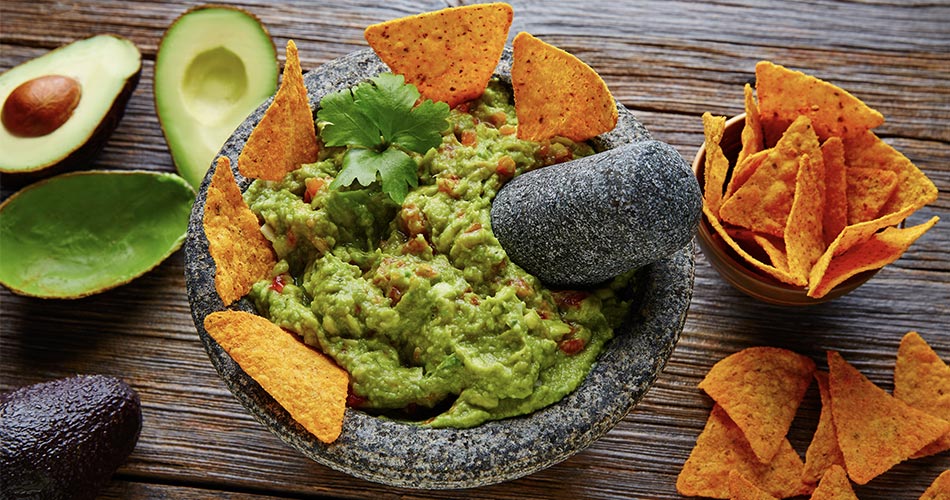 Guacamole in a mortar and pestle with nacho chips