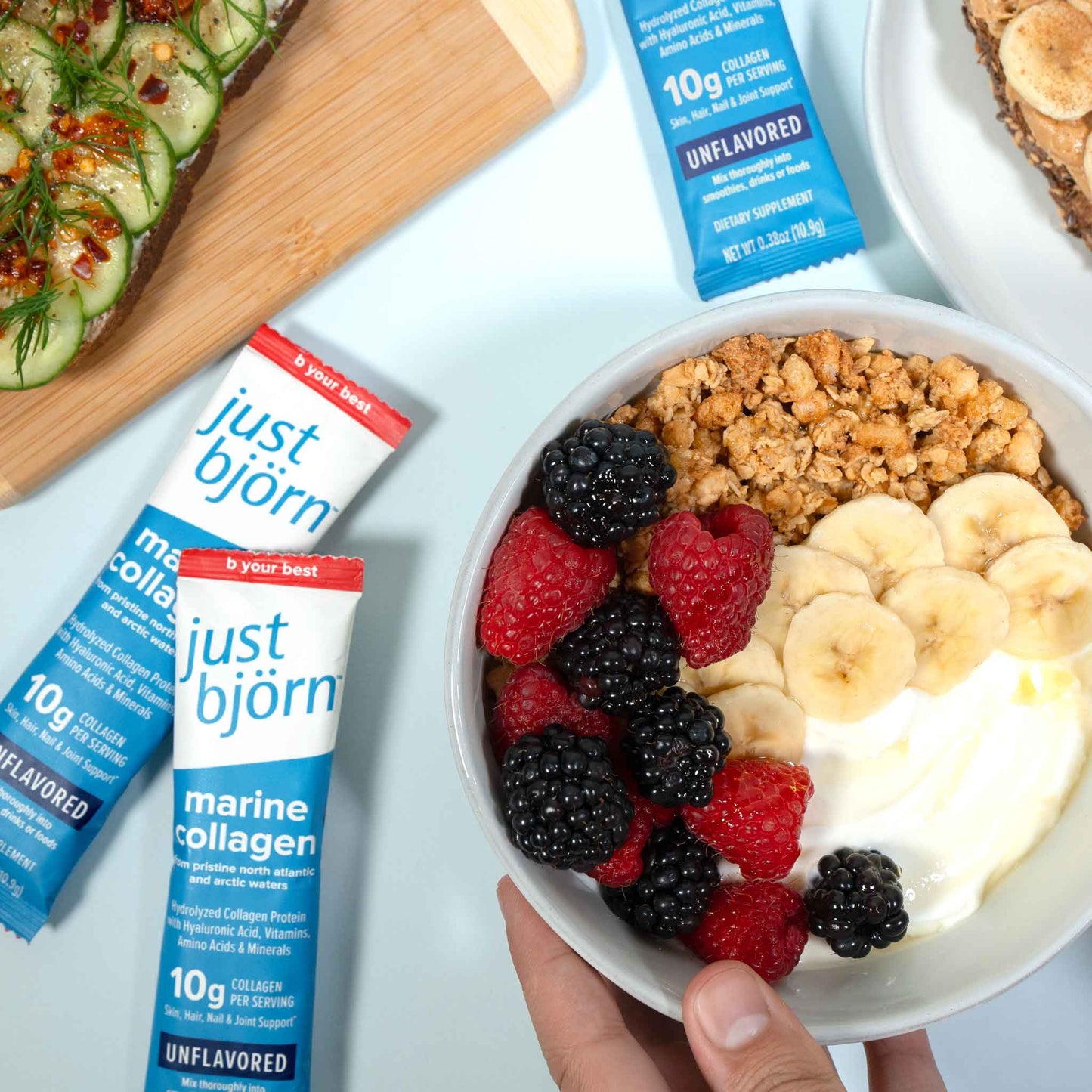 Bowl of yogurt with fruit and granola next to Just Bjorn marine collagen stick packs