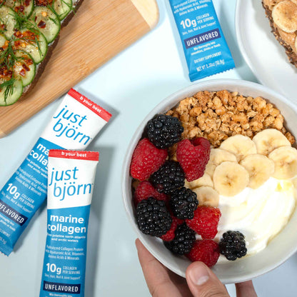 Bowl of yogurt with fruit and granola next to Just Bjorn marine collagen stick packs