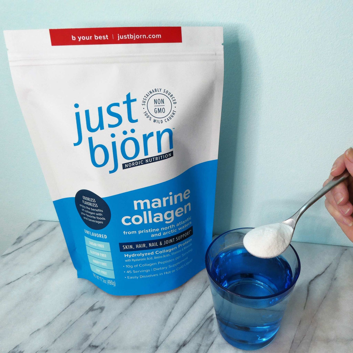 marine collagen being poured into a water glass with the just bjorn pouch in the background