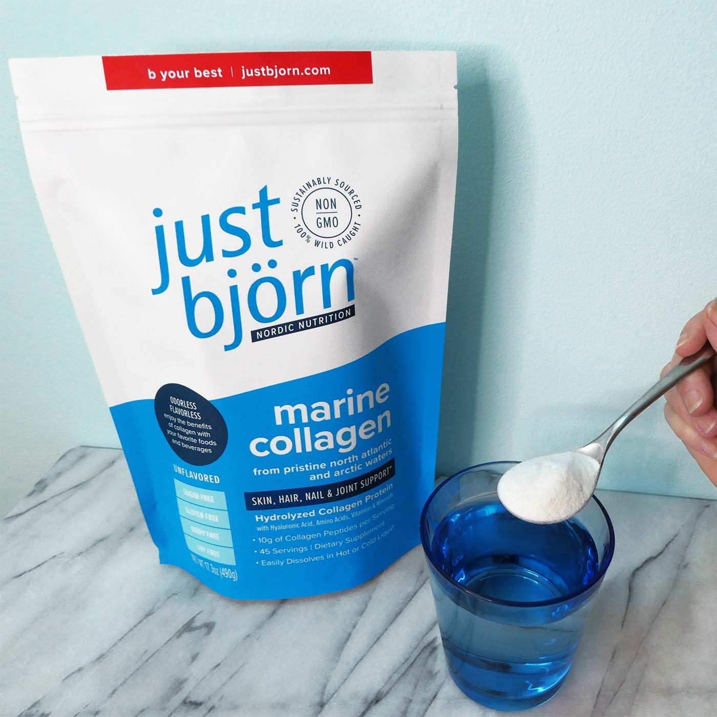 woman pouring just björn marine collagen into her water (product shown in the background)